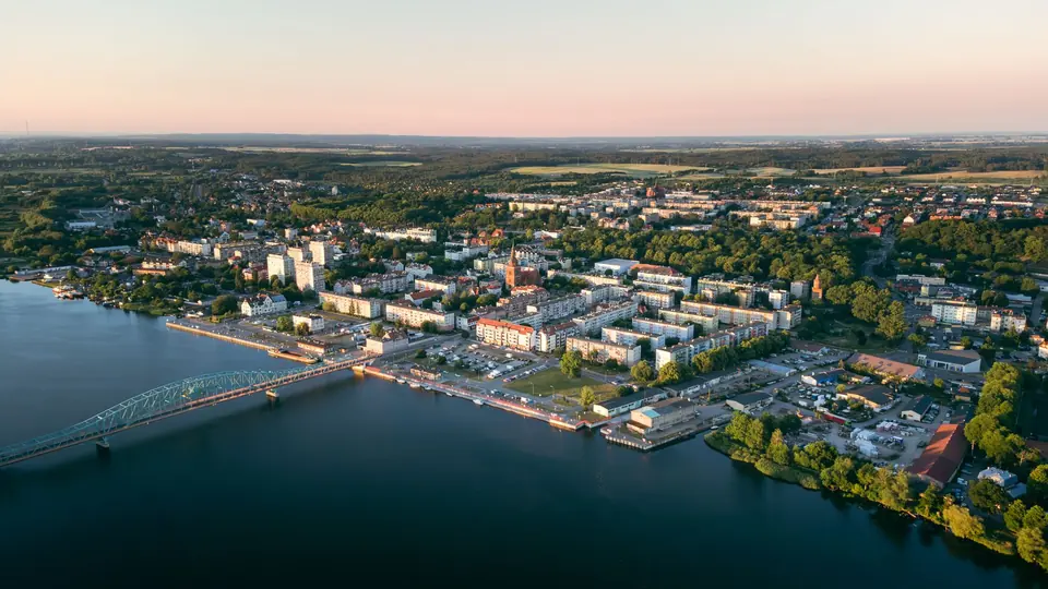 Eine malerische Luftaufnahme von Gryfino, Polen, die die Uferpromenade und die Skyline während eines ruhigen Sonnenuntergangs zeigt.